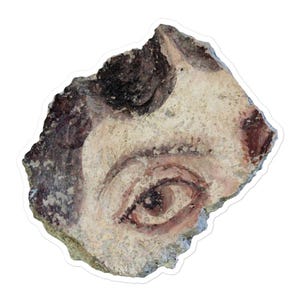 May include: Fragment of ancient artwork featuring a painted eye. The eye is rendered in shades of brown, red, and white, with a detailed depiction of the iris and eyelid. The artwork is on a weathered, textured surface.