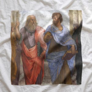 May include: A square fabric print featuring a reproduction of Raphael's School of Athens, depicting two figures in classical robes. The figure on the left wears a red and purple garment, pointing upward, while the figure on the right wears blue.