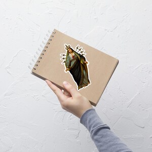 Pode incluir: Uma ilustra&ccedil;&atilde;o de estilo vintage da Virgem Maria, representada com uma coroa e sete espadas que lhe atravessam o cora&ccedil;&atilde;o. A imagem &eacute; feita em um estilo tradicional com cores suaves e detalhes intrincados.