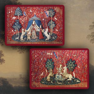 Può includere: Due vassoi decorativi rettangolari con un design arazzo medievale e un bordo rosso. L'arazzo raffigura una dama, un unicorno e altri animali in un ambiente forestale. Lo sfondo è rosso intenso con motivi floreali.