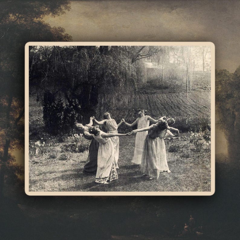 May include: A vintage black and white photograph depicts a group of people in flowing dresses dancing in a circle outdoors. The scene is set in a grassy area with a large tree in the background, creating a sense of movement and celebration.