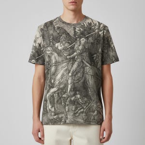 Pode incluir: T-shirt de gola redonda com uma ilustração a preto e branco de um cavaleiro a cavalo, num cenário florestal. A obra de arte detalhada inclui um cão e outras figuras, cobrindo toda a t-shirt.