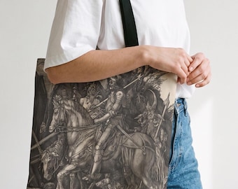May include: A tote bag featuring a detailed monochromatic illustration of a knight in armor riding a horse, accompanied by a horned figure and a dog. The artwork is rendered in shades of gray, black, and cream, depicting a complex scene.