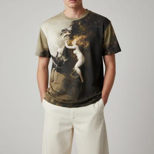May include: Olive green short-sleeve t-shirt featuring a classical painting print. The artwork depicts a nude figure with flowing red hair, embracing a dark horse-like creature. The shirt has a crew neck and a relaxed fit.