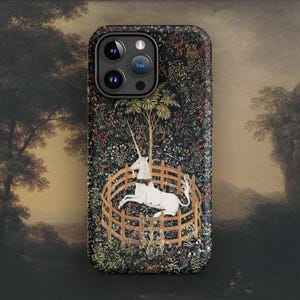 May include: A black phone case with a colorful tapestry design featuring a white unicorn in a circular fence. The tapestry design is reminiscent of the Unicorn Tapestries.