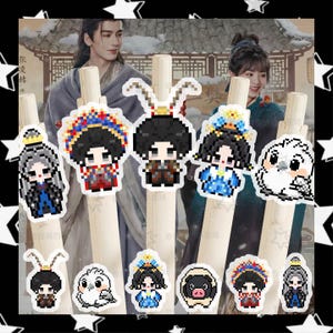 May include: A collection of decorative pens featuring pixelated character designs. The designs include figures with crowns, animal ears, and owl and pig illustrations. The pens are set against a backdrop of a person in traditional clothing.