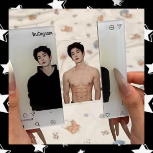Puede incluir: Tarjetas fotográficas de Instagram de acrílico transparente con un hombre con una parte superior negra y sin camisa. Las tarjetas tienen iconos y texto de Instagram. Las tarjetas son sostenidas por una persona con uñas largas.