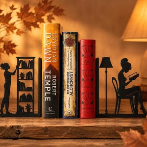 Peut inclure: Une paire de serre-livres en métal noir représentant des silhouettes de personnes lisant et interagissant avec une bibliothèque et un lampadaire. Les serre-livres soutiennent trois livres reliés intitulés Egyptian Dawn, Alchemyst et un livre rouge.
