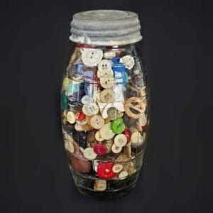 May include: A clear glass jar with a ribbed metal lid, filled with a large collection of assorted sewing buttons in various colors, shapes, and sizes, including white, red, green, blue, brown, and black plastic, wood, and metal fasteners.