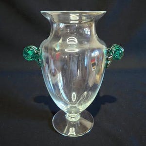 May include: A white ceramic mug with a black handle and the text "But First, Coffee" in a black, bold font. The mug is sitting on a wooden surface. The mug is 4 inches tall.