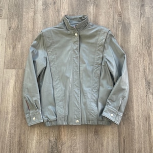 May include: A gray leather jacket with a zipper closure and a stand-up collar.