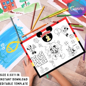 May include: A black and white Mickey Mouse themed coloring placemat with the text "Aaron is 2". The placemat is surrounded by red and yellow borders. The image also includes drawings and colored pencils.