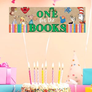 Pode incluir: Um bolo de aniversário com granulado colorido e velas acesas. O bolo é rodeado por presentes embrulhados e balões. Uma faixa acima do bolo diz "ONE for the BOOKS" com ilustrações de personagens de livros.