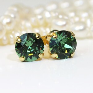 May include: A pair of gold stud earrings with round, dark green gemstones.
