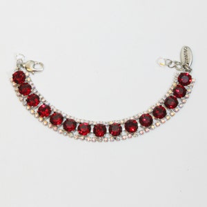 May include: A silver bracelet with a double row of red and clear rhinestones. The bracelet has a silver clasp and the word "TIMATIBO" is printed on the tag.