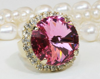 May include: A pink crystal ring with a gold band and a halo of clear rhinestones.