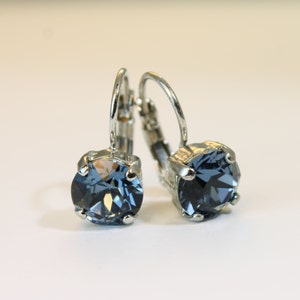 May include: A pair of silver hoop earrings with a blue crystal stone in the center of each hoop.