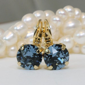 May include: A pair of gold earrings with dark blue crystal stones. The earrings have a lever back closure.