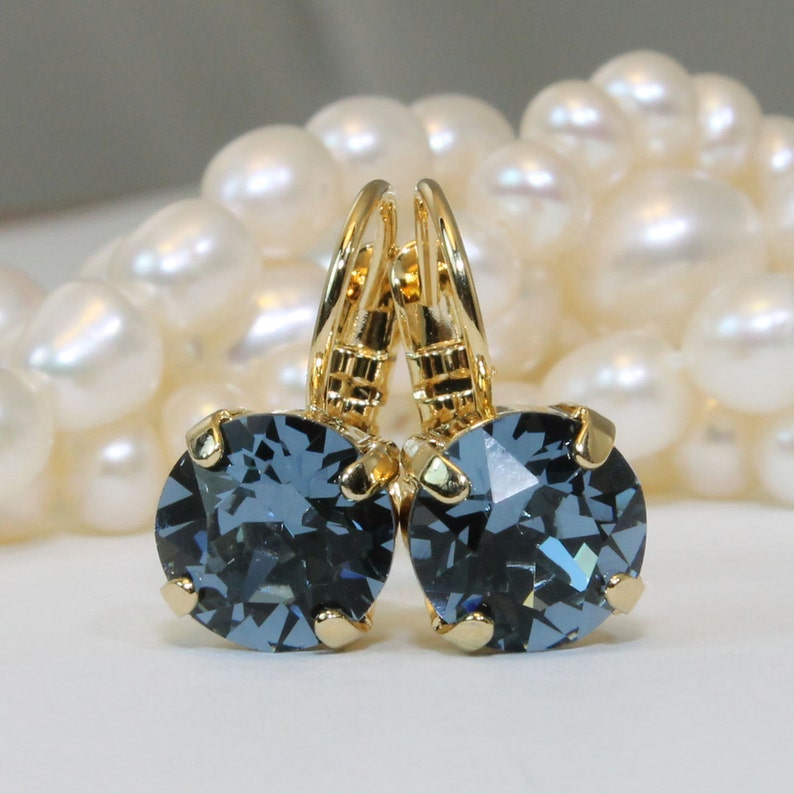 May include: A pair of gold earrings with dark blue crystal stones. The earrings have a lever back closure.