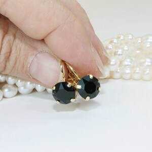 May include: A pair of gold earrings with black round stones. The earrings have a simple design and are perfect for everyday wear.