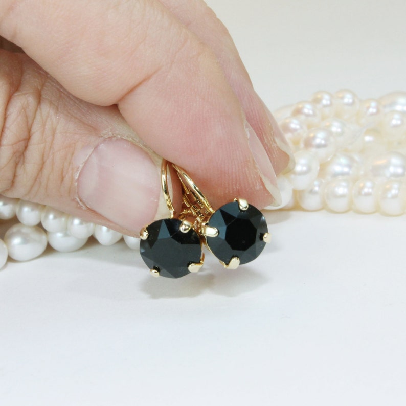 May include: A pair of gold earrings with black round stones. The earrings have a simple design and are perfect for everyday wear.