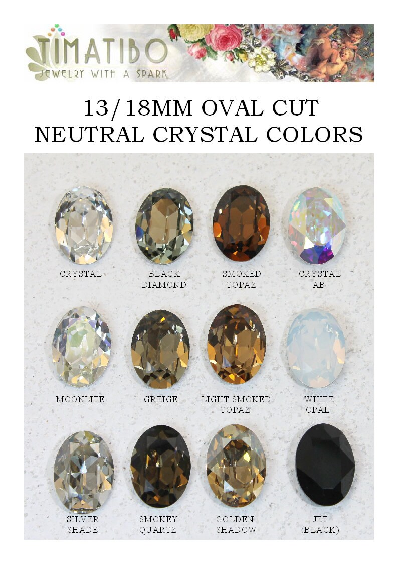 May include: A collection of twelve 13/18mm oval cut crystals in neutral colors labeled as Crystal, Black Diamond, Smoked Topaz, Crystal AB, Moonlite, Greige, Light Smoked Topaz, White Opal, Silver Shade, Smokey Quartz, Golden Shadow, and Jet Black.