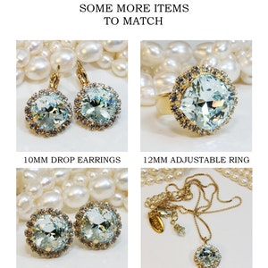 May include: Four pieces of jewellery featuring light blue crystal stones set in gold. The jewellery includes a pair of drop earrings, a pair of stud earrings, a ring, and a necklace. The jewellery is displayed on a background of white pearls.