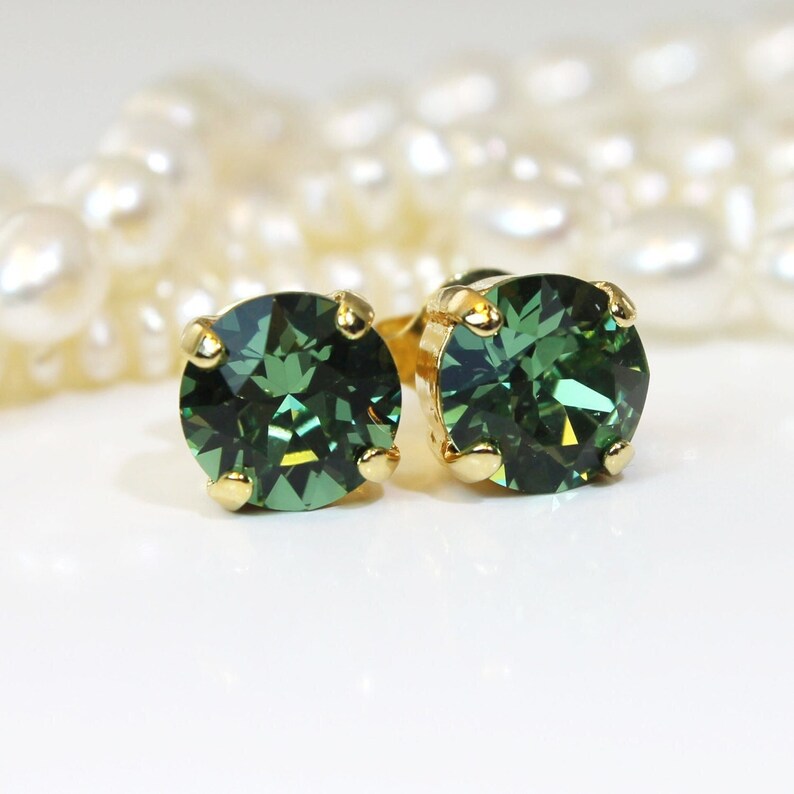 May include: A pair of gold stud earrings with round, dark green gemstones.