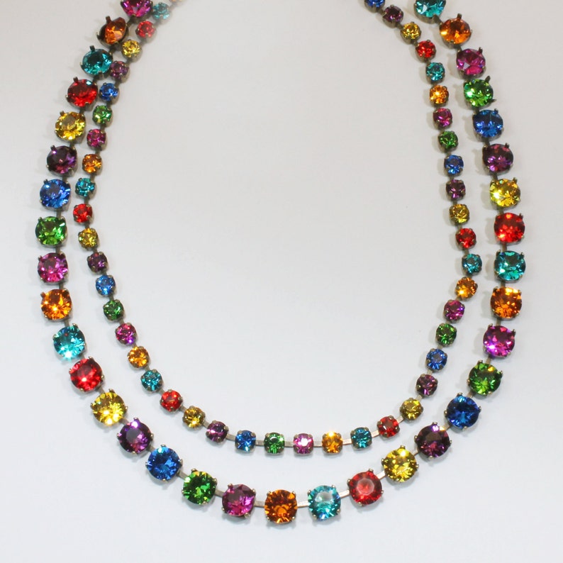 Puede incluir: Un collar de doble cadena con piedras redondas de colores arco&iacute;ris. El collar est&aacute; hecho de metal y tiene un dise&ntilde;o sencillo.