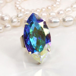 May include: A large, faceted, iridescent blue and green gemstone ring with a marquise cut. The ring is set in a silver band.