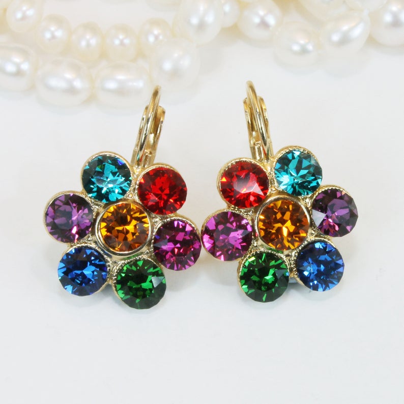 Puede incluir: Un par de pendientes de oro en forma de flor con piedras de cristal de colores. Las piedras est&aacute;n dispuestas en un patr&oacute;n de arco&iacute;ris, con piedras rojas, naranjas, amarillas, verdes, azules y moradas.