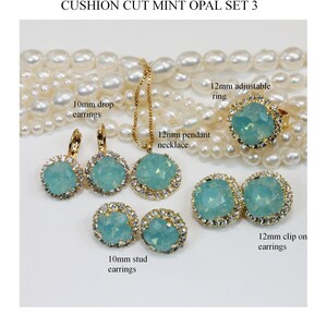 May include: A set of mint green opal jewellery with gold settings. The set includes a necklace, a ring, a pair of drop earrings, and a pair of stud earrings. The jewellery is made with Swarovski elements.