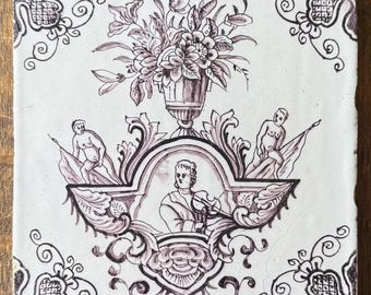 Azulejo holandés de Rotterdam del siglo XVIII con cartela: jarrón floral de manganeso y querubines, sin restaurar.