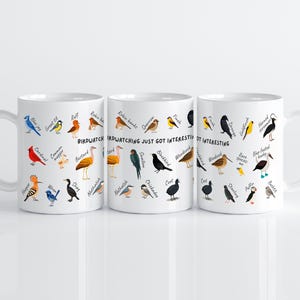 May include: Three white ceramic mugs with colorful illustrations of various birds and their names. The mugs have the text "Birdwatching just got interesting". The birds are in different colors and poses.