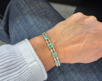 May include: A bracelet with green and blue square beads and silver spacer beads.