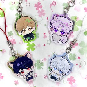 May include: Four acrylic charms featuring chibi-style anime characters with distinct hair colors and outfits. Each charm includes a metal lobster clasp and a cord attachment. The characters have large eyes and are printed with the text douhwuadays.
