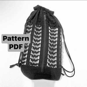 Könnte beinhalten: Schwarze gehäkelte Kordeltasche mit Reißverschluss. Die Tasche hat ein Muster aus kleinen Quadraten und ist aus dickem Garn gefertigt. Der Text "SleepingFruitBasket" ist auf der Tasche sichtbar.