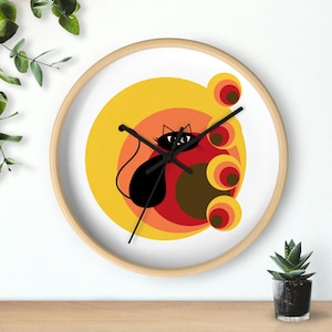 May include: A round wall clock with a white face and a black cat design. The cat is sitting in the center of a series of concentric circles in shades of yellow, orange, and red.