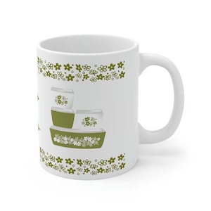 May include: White ceramic mug with a green floral pattern. The pattern features a stack of three green and white bowls with a floral design. The mug has a white handle.