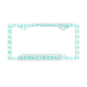 May include: A white license plate frame with a turquoise pattern of stylized birds and flowers.