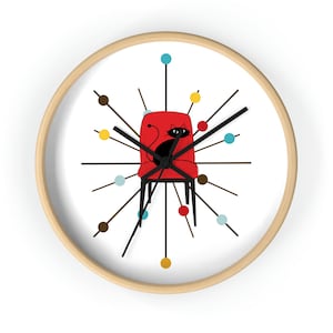 May include: A white clock face with a red chair and a black cat sitting in it. The clock has brown, red, yellow, and blue accents.