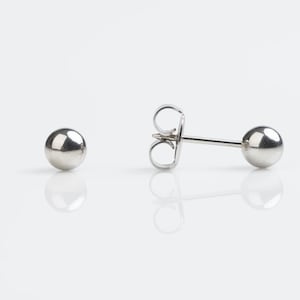 May include: A pair of silver stud earrings with a round ball design.