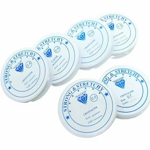 May include: Six spools of white elastic string with blue diamond logos and text that reads "Strong & Stretchy" and "Crystalline". The spools are labelled with different sizes: 0.4, 0.5, 0.6, 0.7, 0.8, and 1.0.