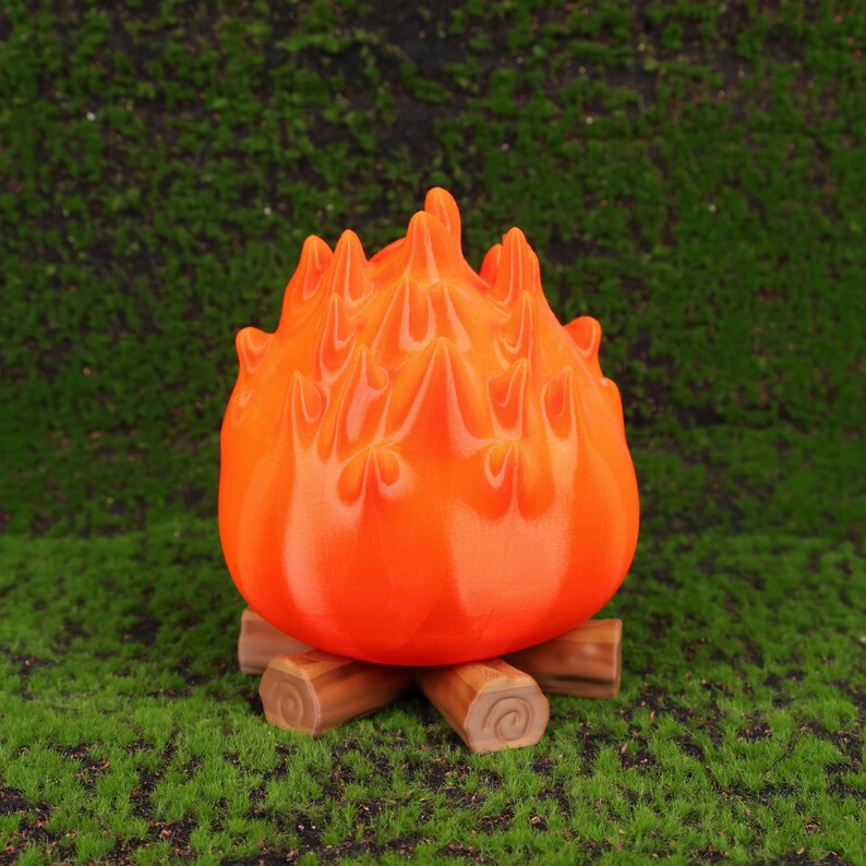 Desktop setup featuring the Fire Demon Calcifer-inspired organizer in a cozy home office environment. The piece is used to store SD cards, USB drives, and earbuds, demonstrating its practical utility while also showcasing its artistic design. With its Studio Ghibli inspiration and compact size, this desk accessory is ideal for anime lovers and collectors looking for functional decor.