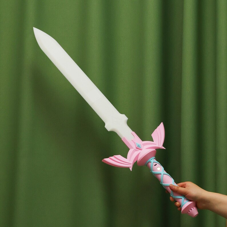 Puede incluir: Una espada de pl&aacute;stico rosa y blanca con un mango azul claro y una hoja blanca. La espada tiene un dise&ntilde;o decorativo en el mango y una cinta azul claro.