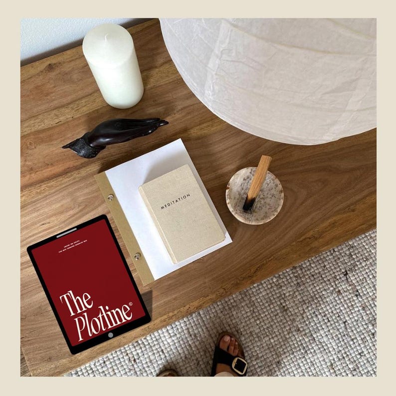 May include: A wooden table with a white candle, a small wooden sculpture, a white paper lantern, a small book titled "Meditation", a small bowl with a stick of incense, and a tablet with the text "The Plotline" on the screen.