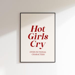 May include: A white framed poster with the text "Hot Girls Cry" in red font. Below the text is the phrase "over fictional characters" in smaller red font.