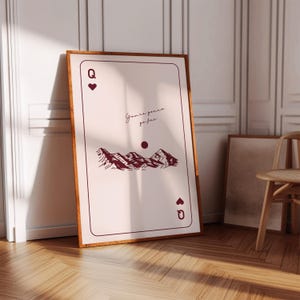 Puede incluir: Una impresión de arte imprimible que presenta una carta de juego de la Reina de Corazones con una ilustración de una cordillera y el texto "You're gonna go far".