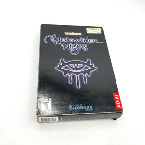 May include: A black rectangular PC game box for Neverwinter Nights featuring the Forgotten Realms logo, a stylized eye graphic with purple glowing edges, the Bioware Corp logo, an Atari logo, and an ESRB Teen rating symbol on the front cover.