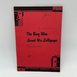 May include: A vintage book cover for "The King Who Loved His Lollipops" by Lila Beldock Cohen. The cover is red with black accents and features stylized illustrations and handwritten notes. The Dramatic Publishing Company is listed.